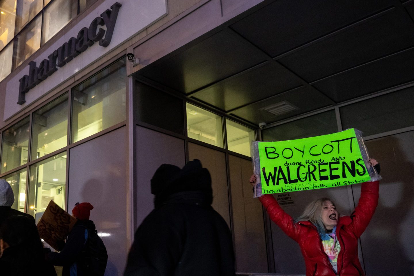 A woman shouts while holding a "boycott Duane Reade and Walgreens" sign stands outside a Duane Reade in Union Square on March 8, 2023 in New York City.
