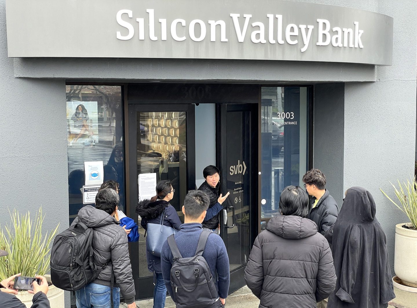 A worker (center) tells people that the Silicon Valley Bank headquarters is closed on Friday in Santa Clara, Calif. SVB was shut down that morning by California regulators and put in control of the U.S. Federal Deposit Insurance Corporation.