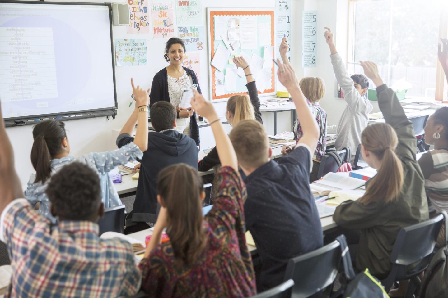 A classroom with students raising their hands