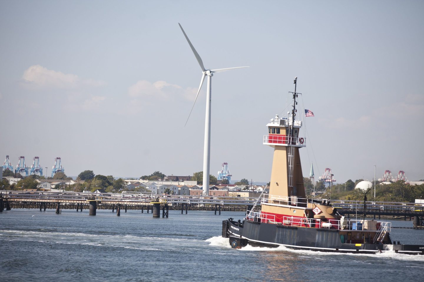 A tugboat drives by wind turbine is placed off the coast in Newark Bay in Elizabeth, New Jersey