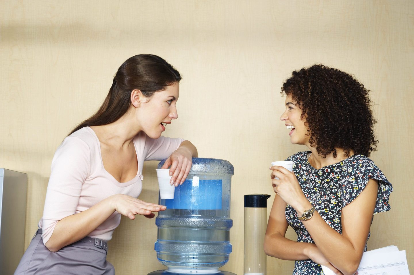 Women chatting next to a water cooler.