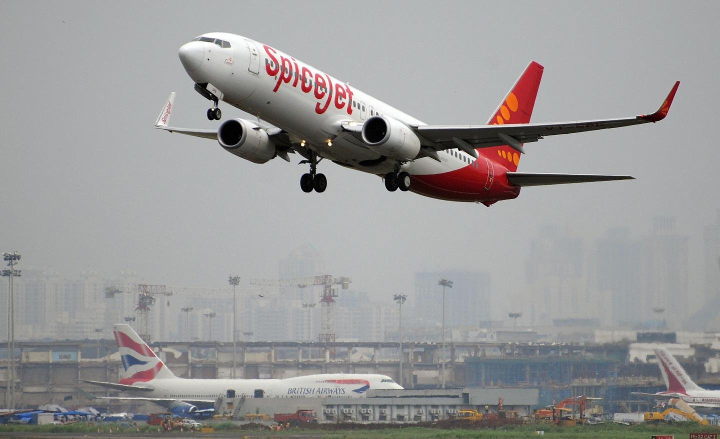 An Indian-operated SpiceJet Boeing 737-800 aircraft takes off as a British Airways Boeing 747-400 aircraft sits on the tarmac at the international airport in Mumbai on October 1, 2009.