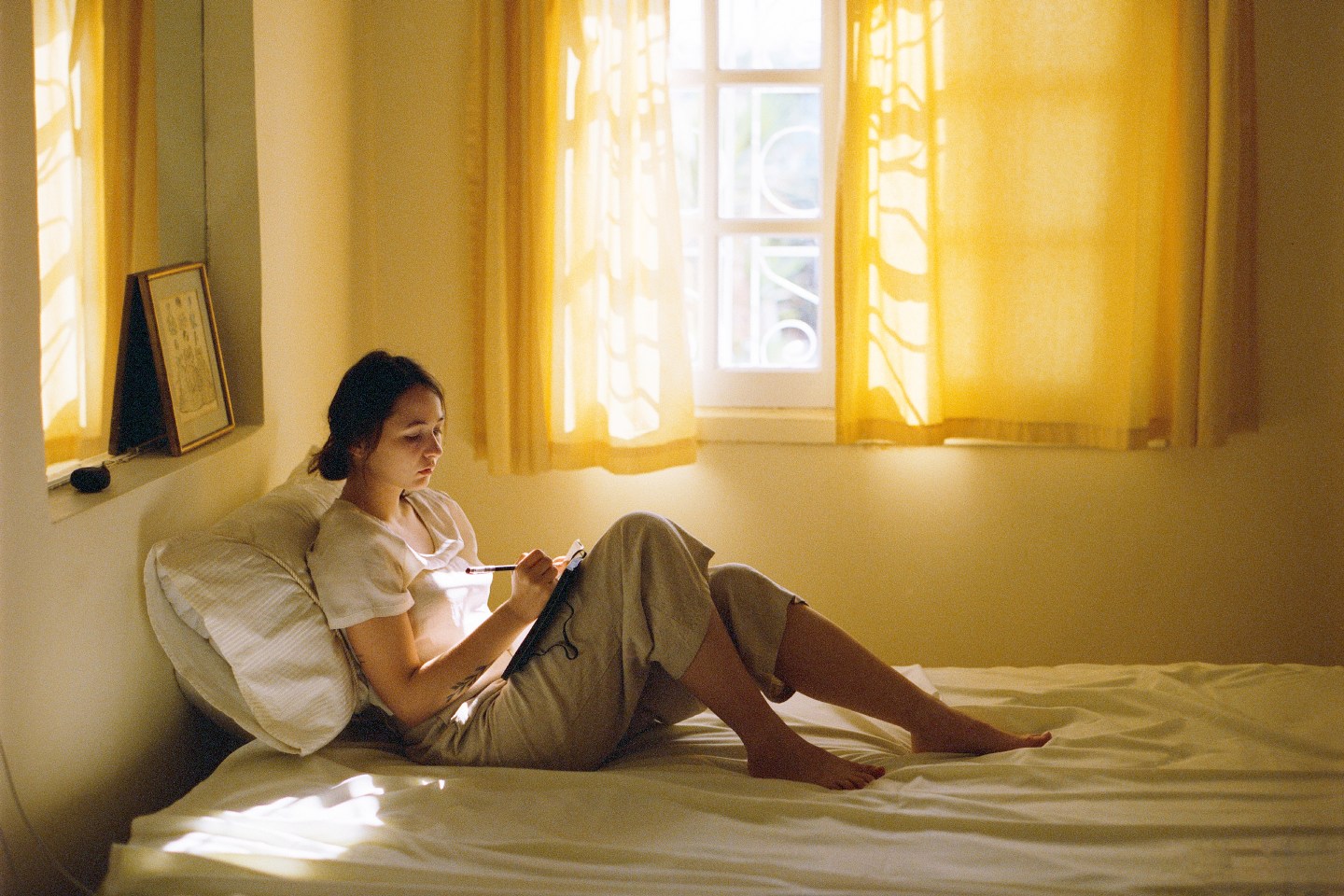 Woman sitting on the bed and writing in diary.