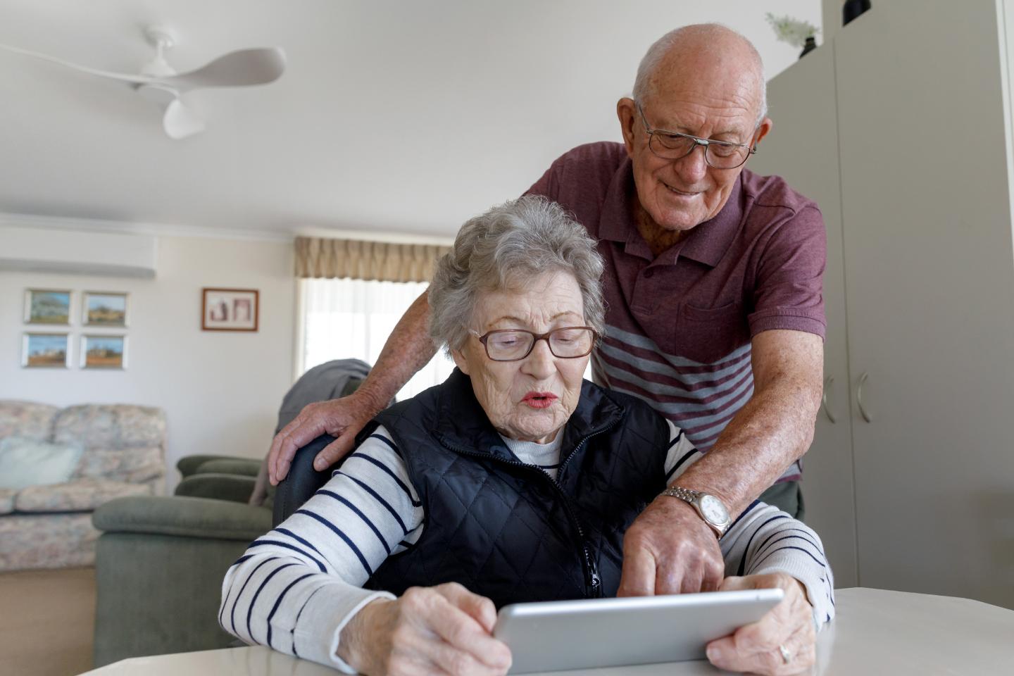 Senior couple looking at digital tablet at home.
