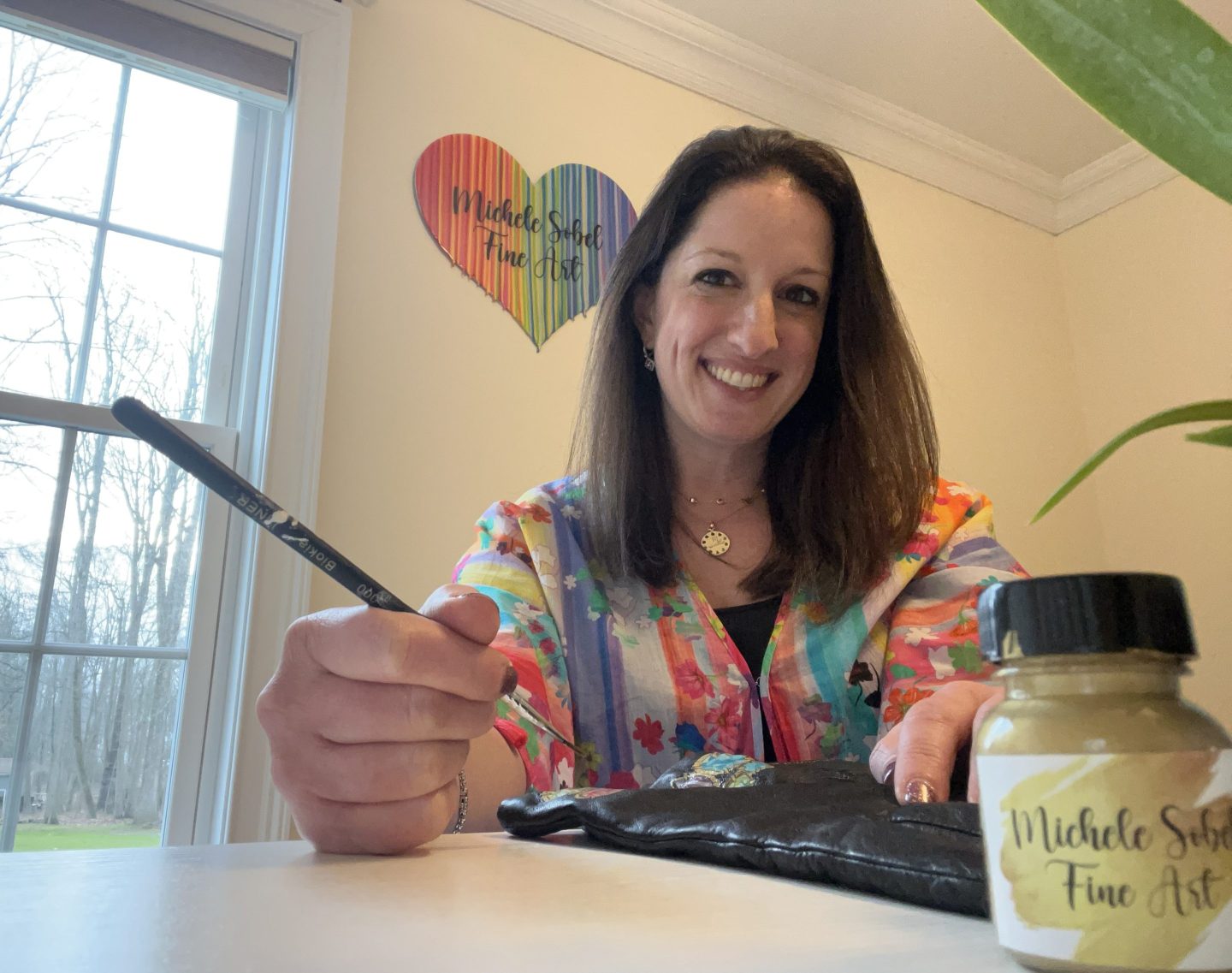 Michele Sobel in the studio adding the finishing touches on a hand-painted leather glove.