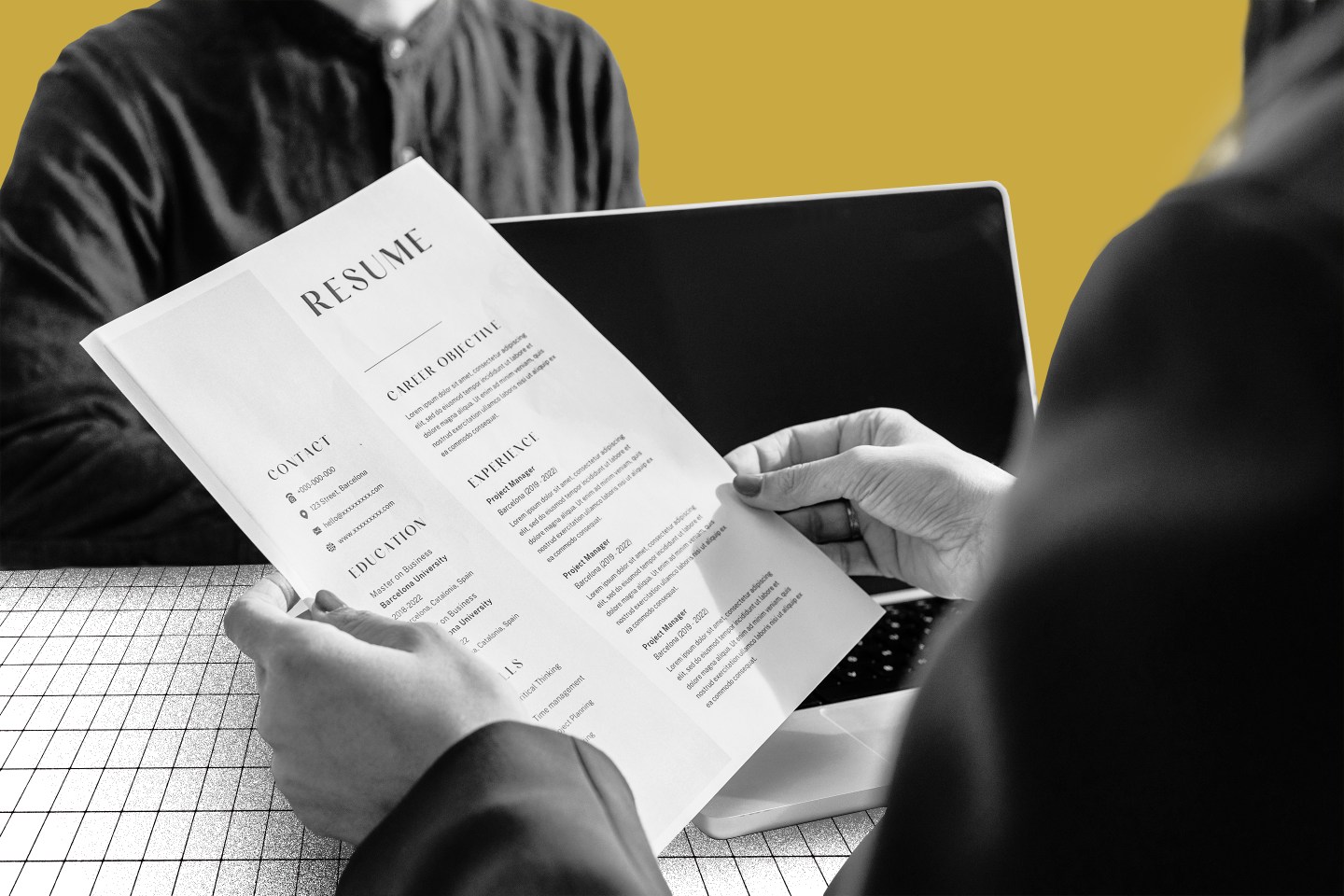 Photo illustration of an interviewer reviewing a person's resume as they sit opposite each other.