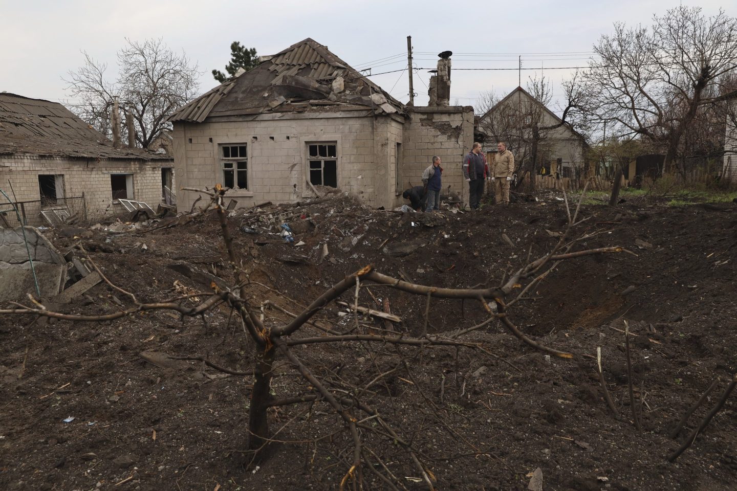 Local residents stand near a crater left by a Russian missile in Zaporizhzhia, Ukraine, on April 9, 2023. An 11-year old girl and her father were killed in the rocket attack in Zaporizhzhia.
