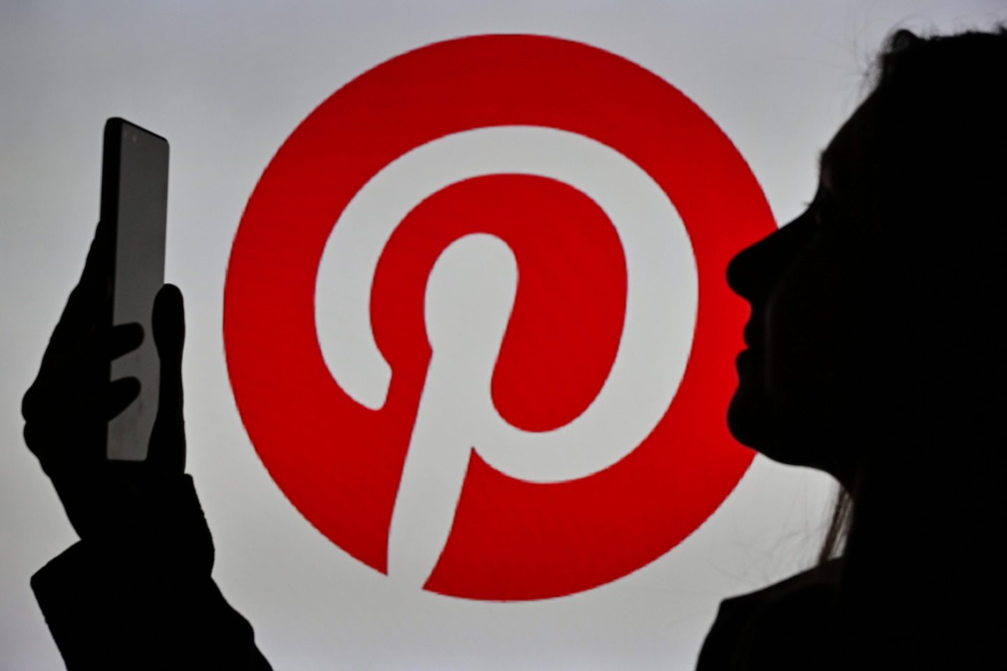 Image of a woman holding a cell phone in front of a Pinterest logo