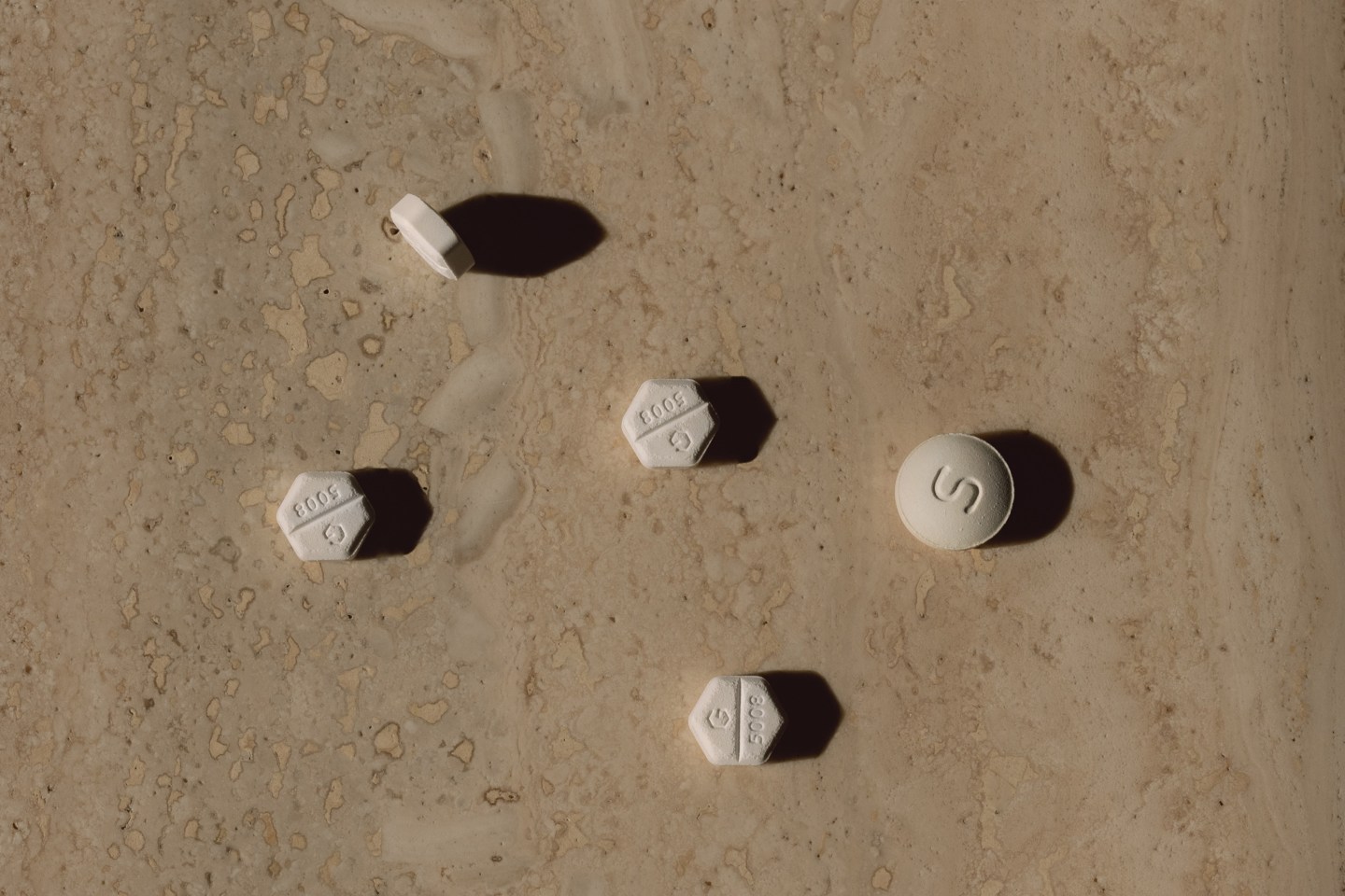 Closeup of pills laying on a tabletop with side lighting