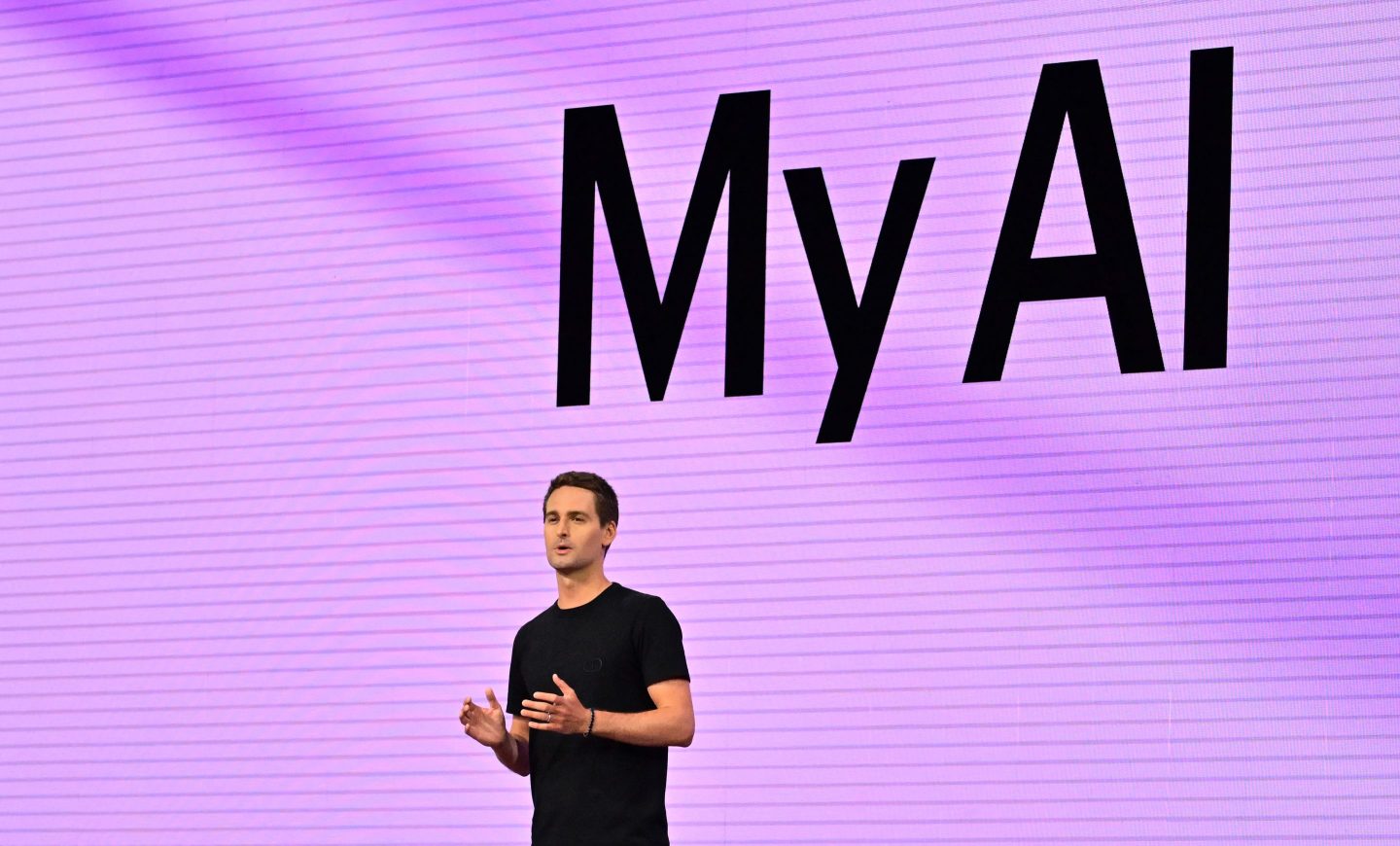 Photo of Snap CEO Evan Spiegel in front of a purple background with a giant 'My AI' projected behind him.