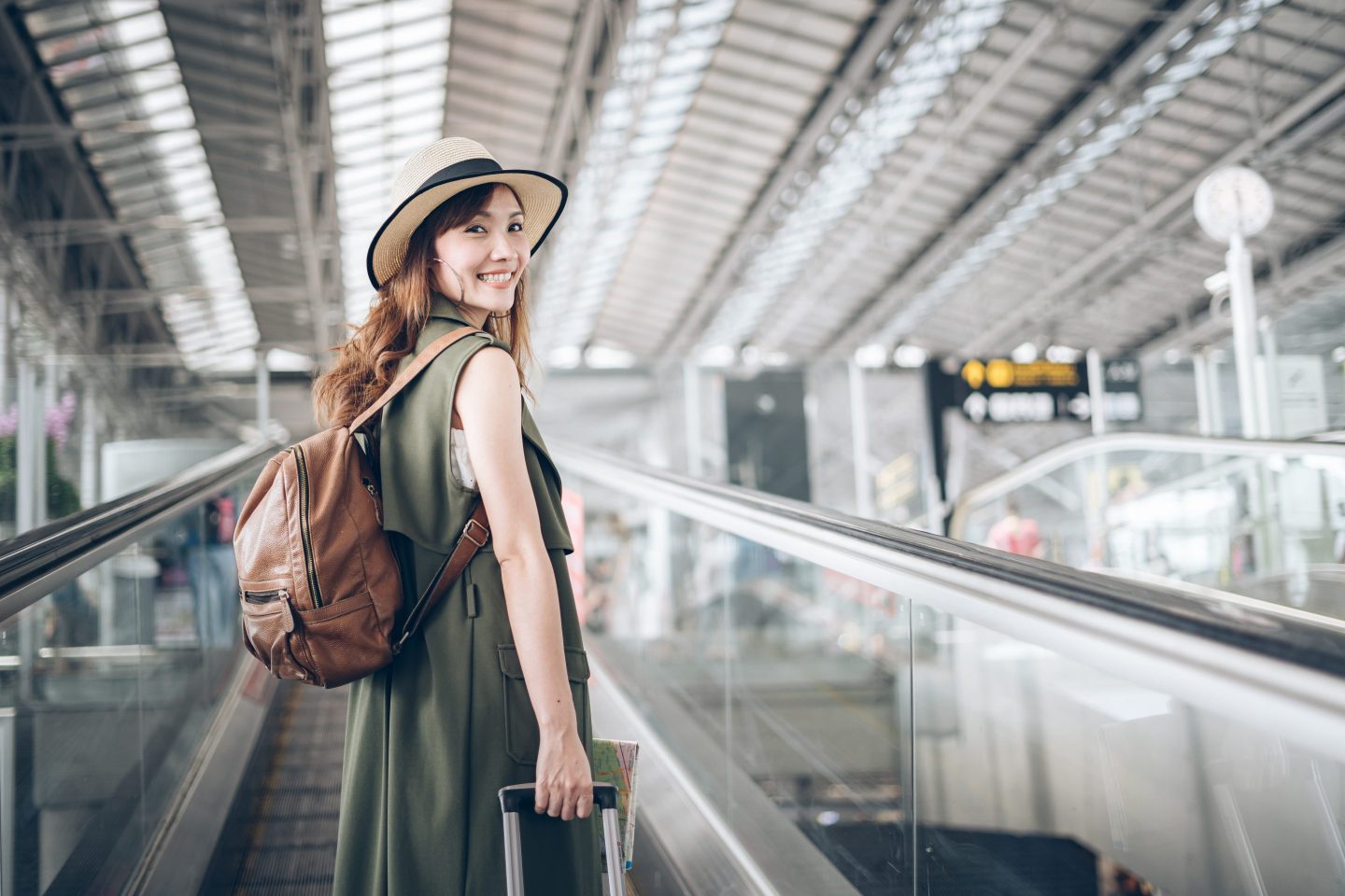 A tourist stands smiling on an airport escalator