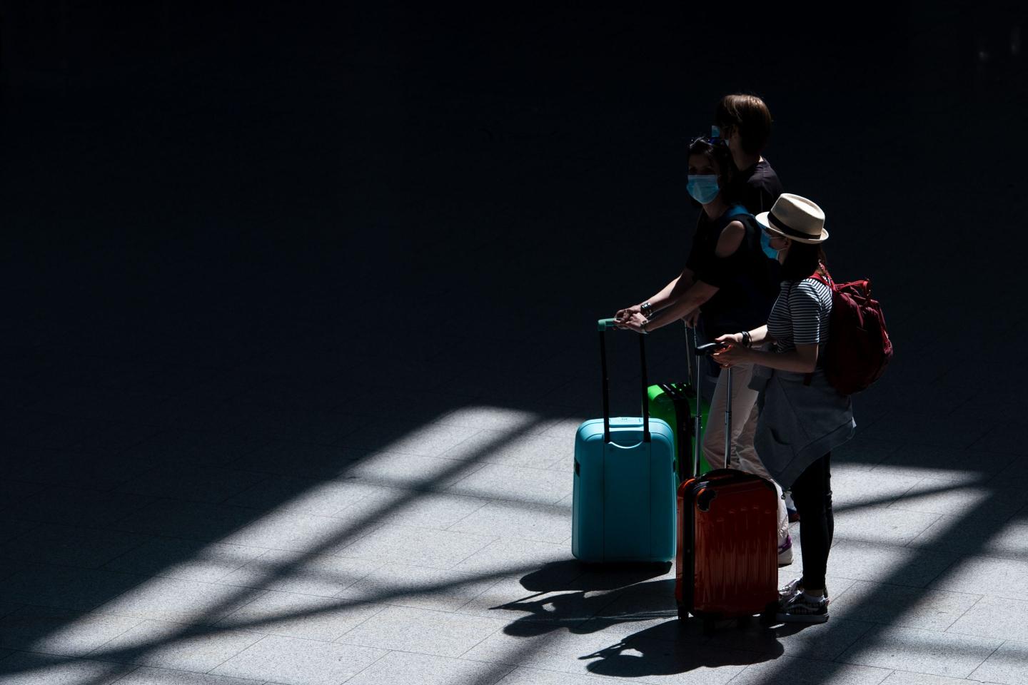 Travelers walk through the airport departure hall with their suitcases.