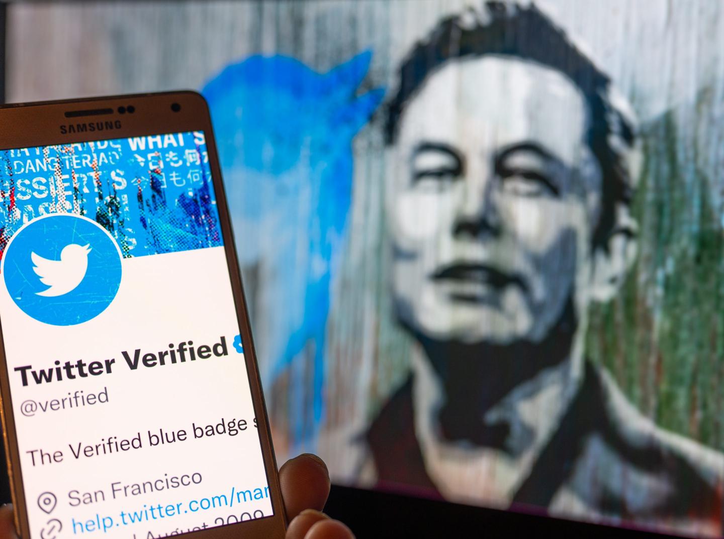 Illustration of a wall graffiti of Elon Musk's face and a cellphone with a verified Twitter badge image