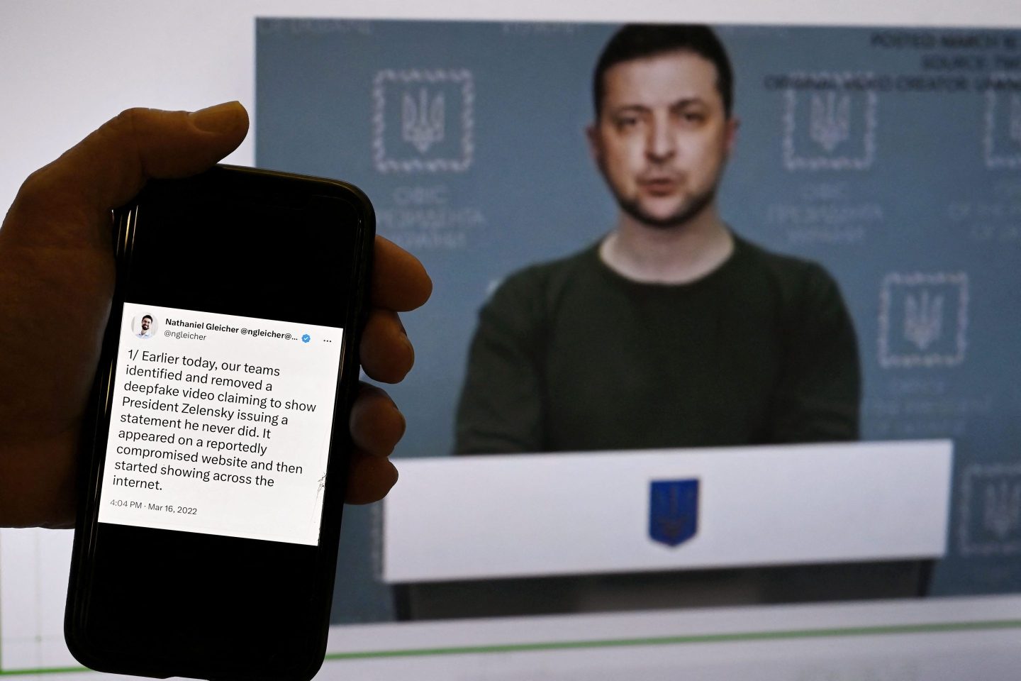This illustration photo taken on January 30, 2023 shows a phone screen displaying a statement from the head of security policy at META with a fake video of Ukrainian President Volodymyr Zelensky calling on his soldiers to lay down their weapons shown in the background, in Washington, DC.