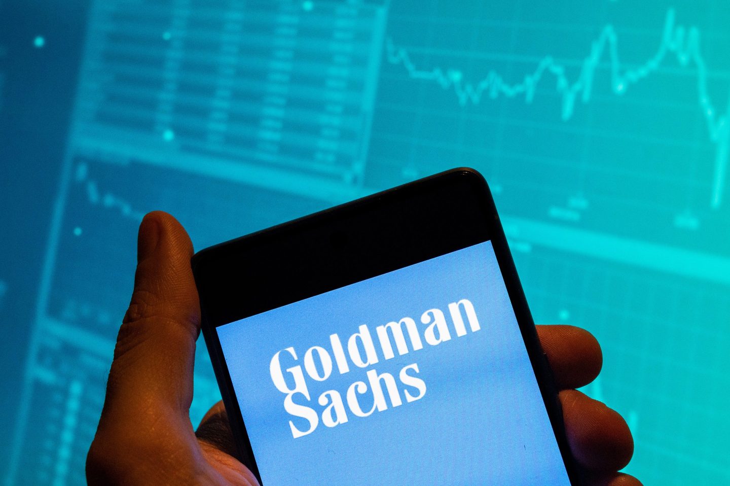 Photo illustration showing a mobile phone displaying the Goldman Sachs logo.