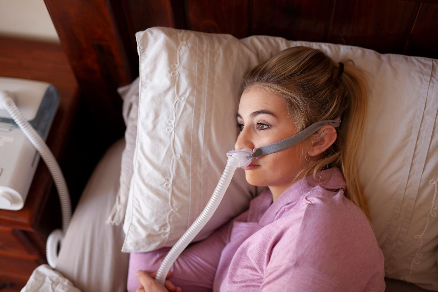 Woman hooked up to a CPAP machine tries to fall asleep