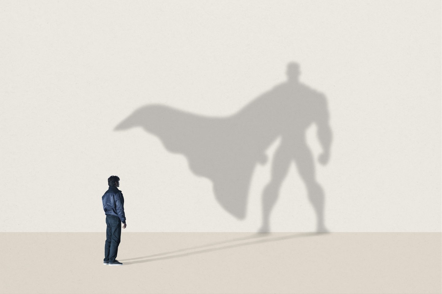 Young man standing in front of large superhero shadow
