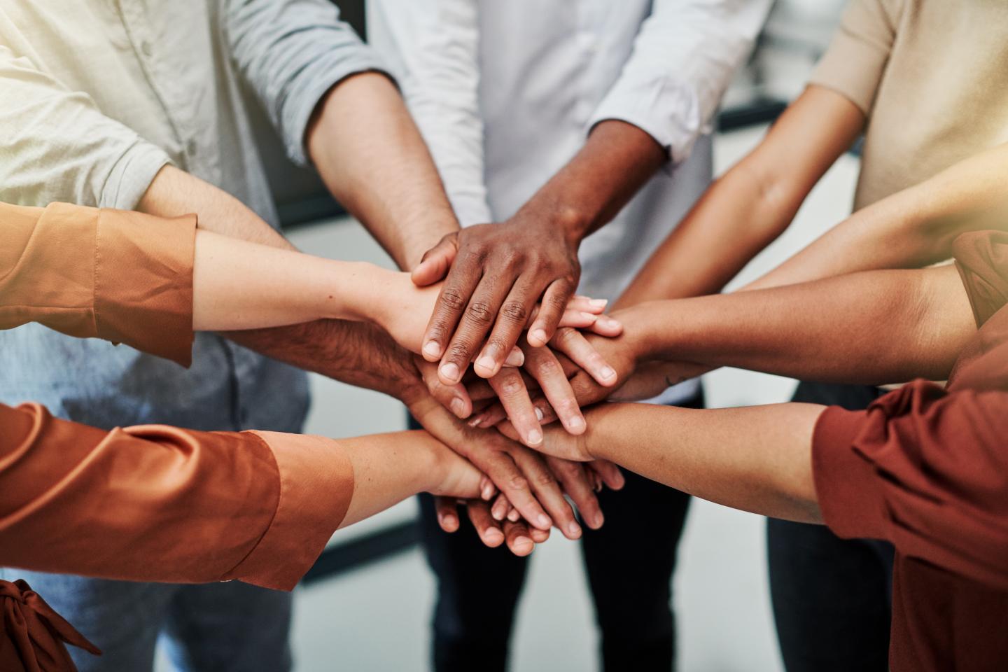 High angle shot of a group of unrecognisable businesspeople joining their hands together in a huddle