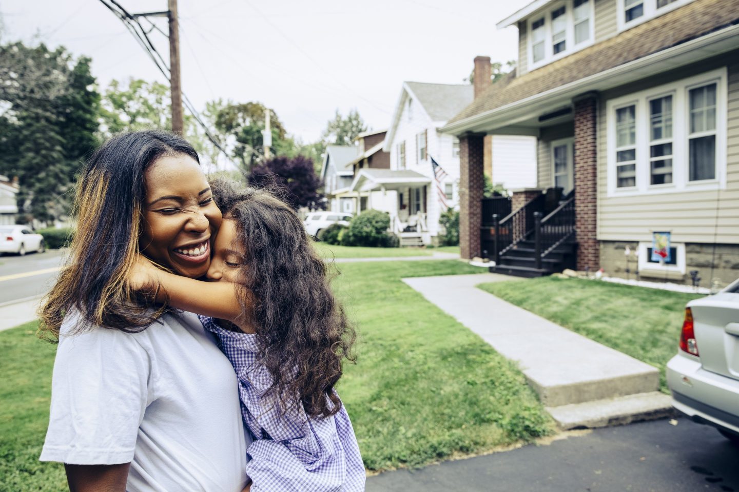 Girl embracing mother in front yard