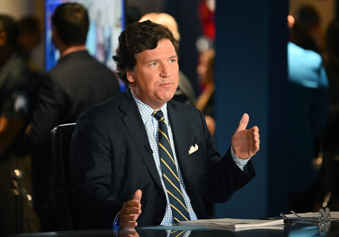 A picture of Tucker Carlson sitting at a desk