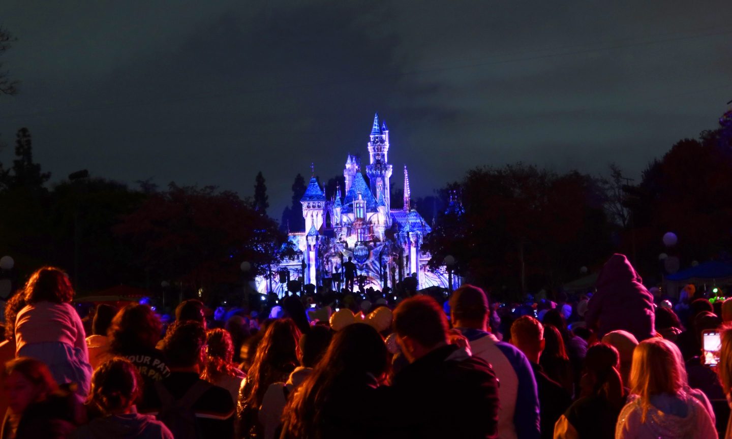People watch the evening light show on the Sleeping Beauty Castle at the Disneyland theme park in Anaheim, Calif.