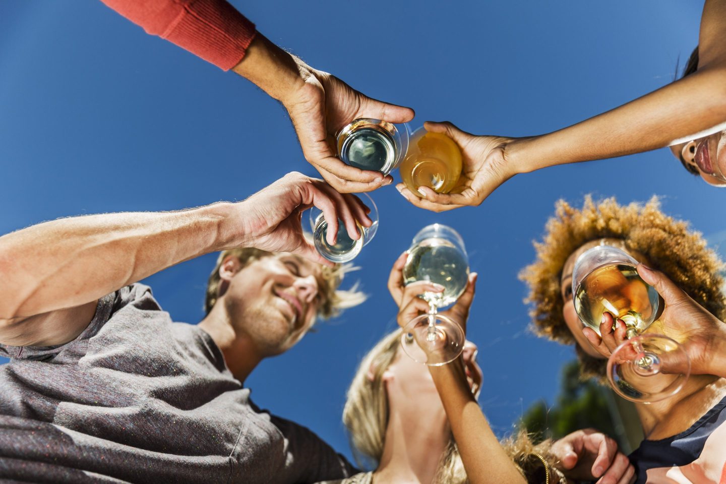 Group of friends outside celebrating with a toast on a bright day.