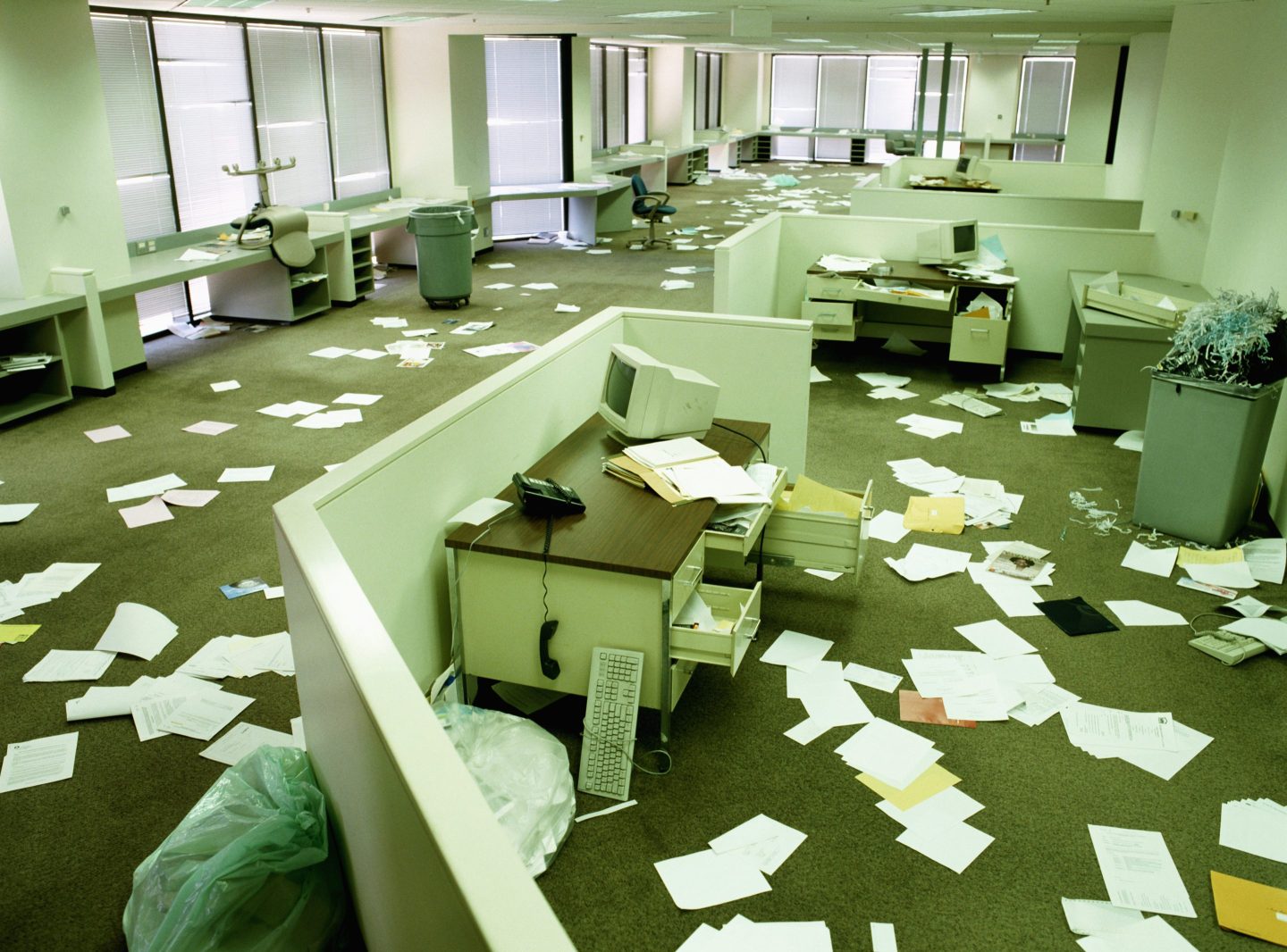 An abandoned office in disarray, with papers on the floor