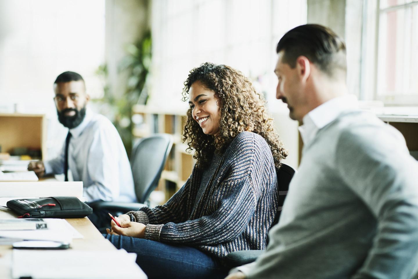 Laughing coworkers in discussion at workstation in office