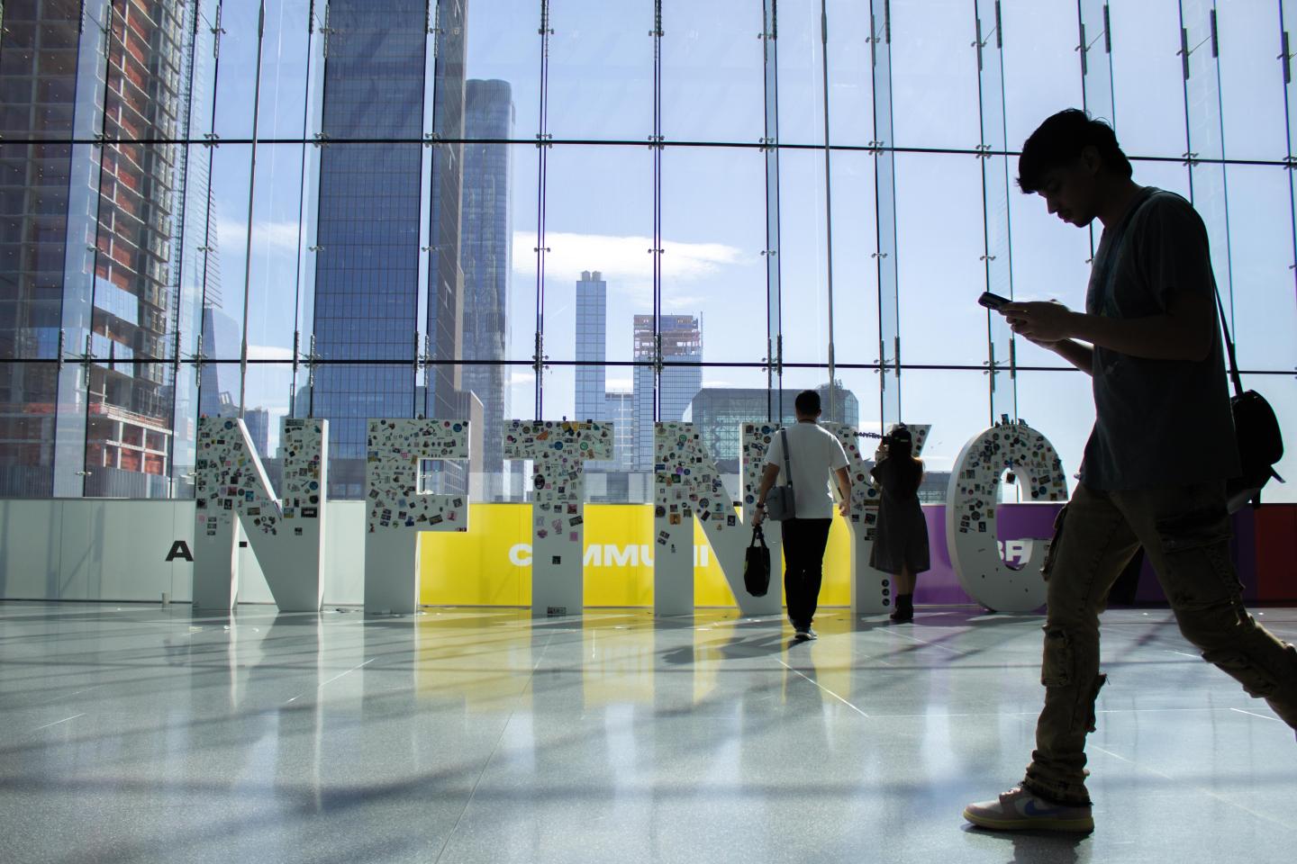 A passerby walks in front of the NFT.NYC sign.