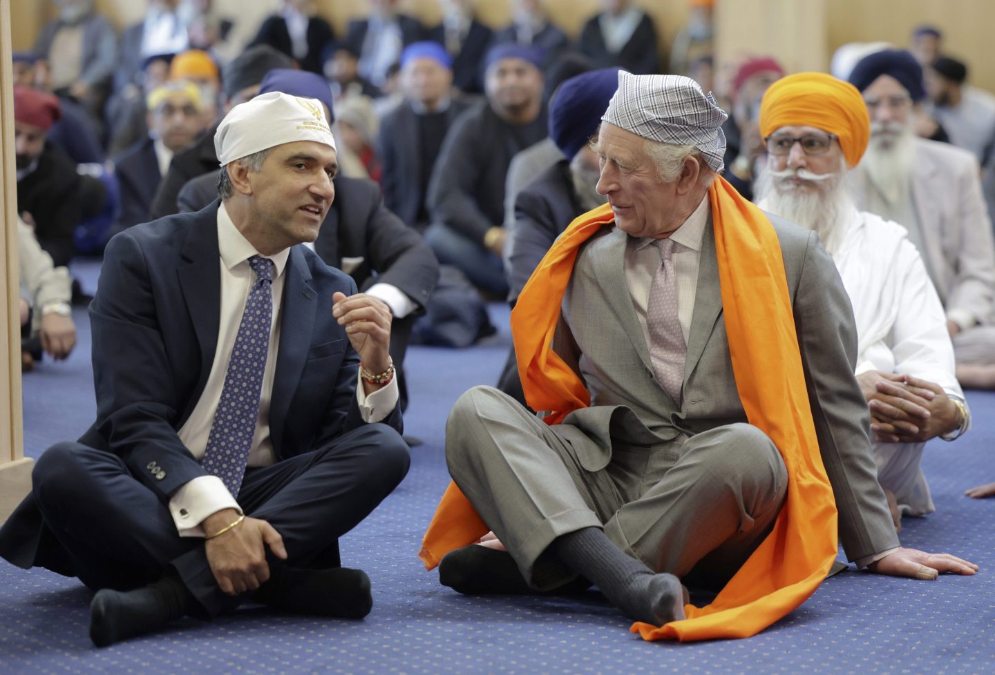 Britain's King Charles III, right, speaks with Professor Gurch Randhawa, a member of the Sikh Congregation, as they sit on the floor in the Prayer Hall during the king's visit to the newly built Guru Nanak Gurdwara, in Luton, England, Tuesday, Dec. 6, 2022.