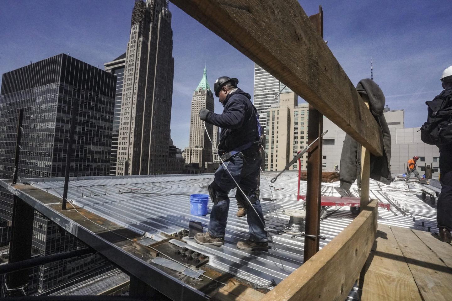 Construction workers install roofing on a high rise in Manhattan's financial district on Tuesday, April 11, 2023, in New York.