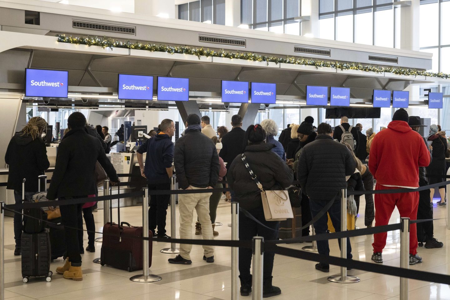 Passengers wait in line to check in for their flights at Southwest Airlines service desk at LaGuardia Airport, on Dec. 27, 2022, in New York.