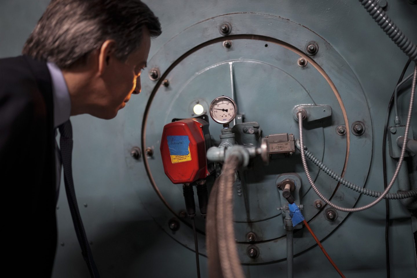 Josh London, senior vice president at Glenwood Management Corp., peers into the port hole of a natural gas fired boiler, located in the basement of The Grand Tier luxury apartment building, that his company uses to produce liquid carbon dioxide, on April 18, 2023, in New York.