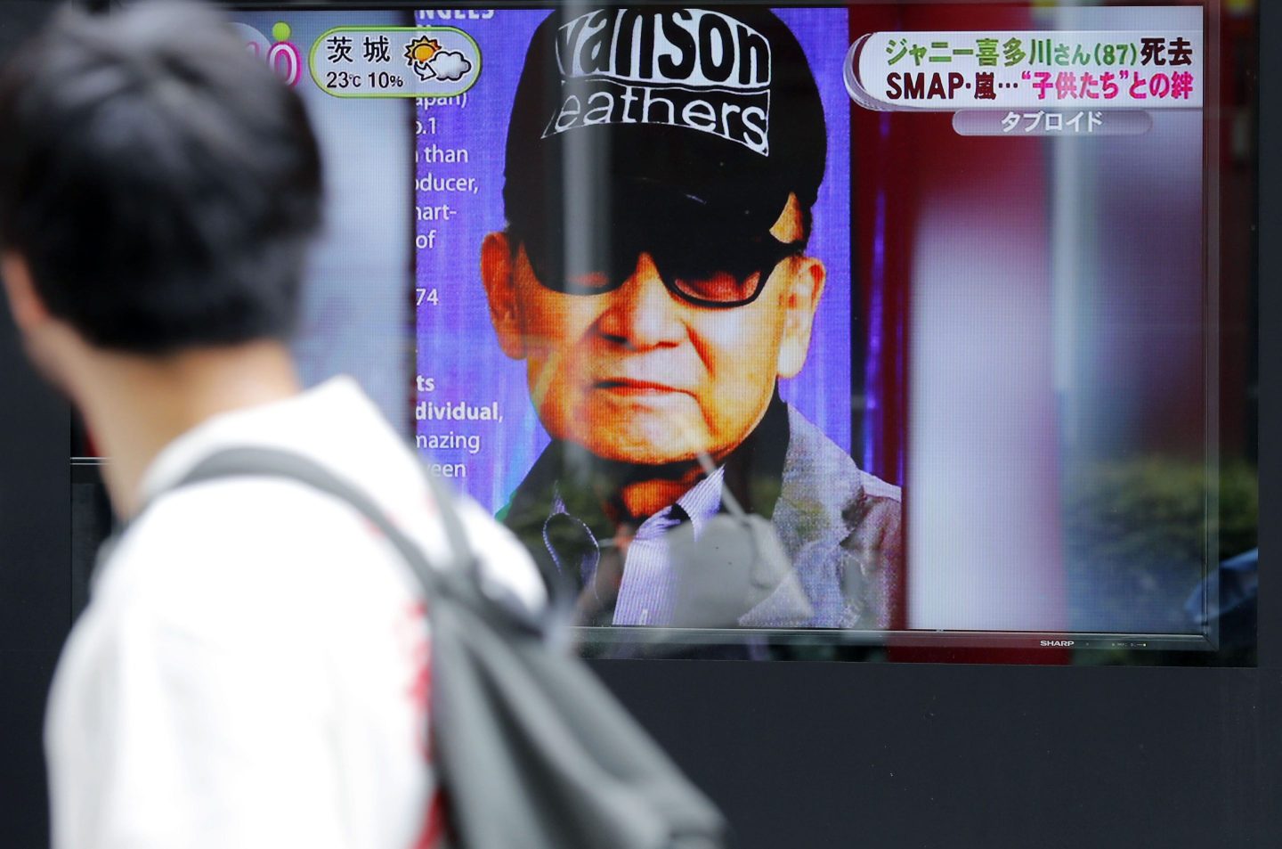 A passer-by watches news reporting on the death of Johnny Kitagawa, founder of Johnny's talent agency, in Tokyo, July 10, 2019.