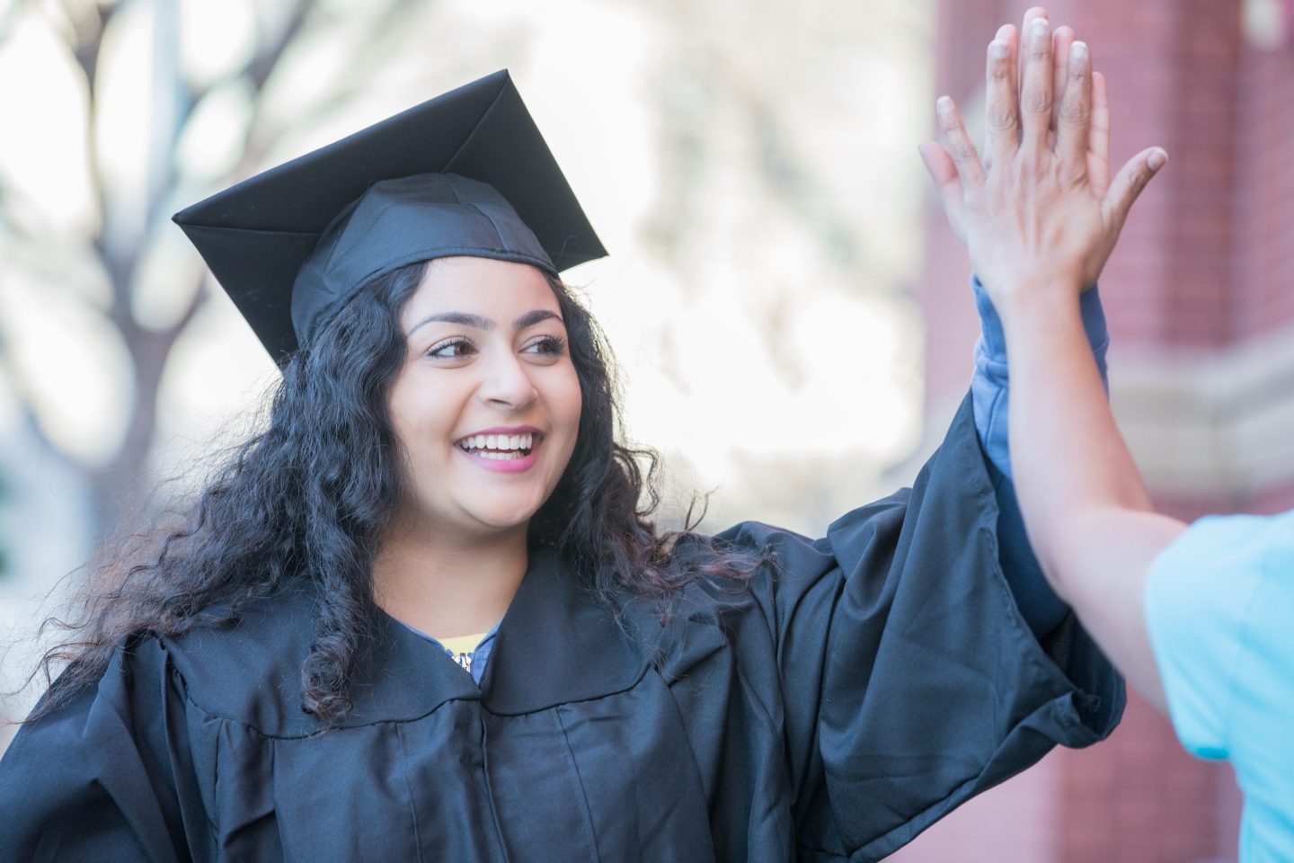 woman at graduation high-fiving