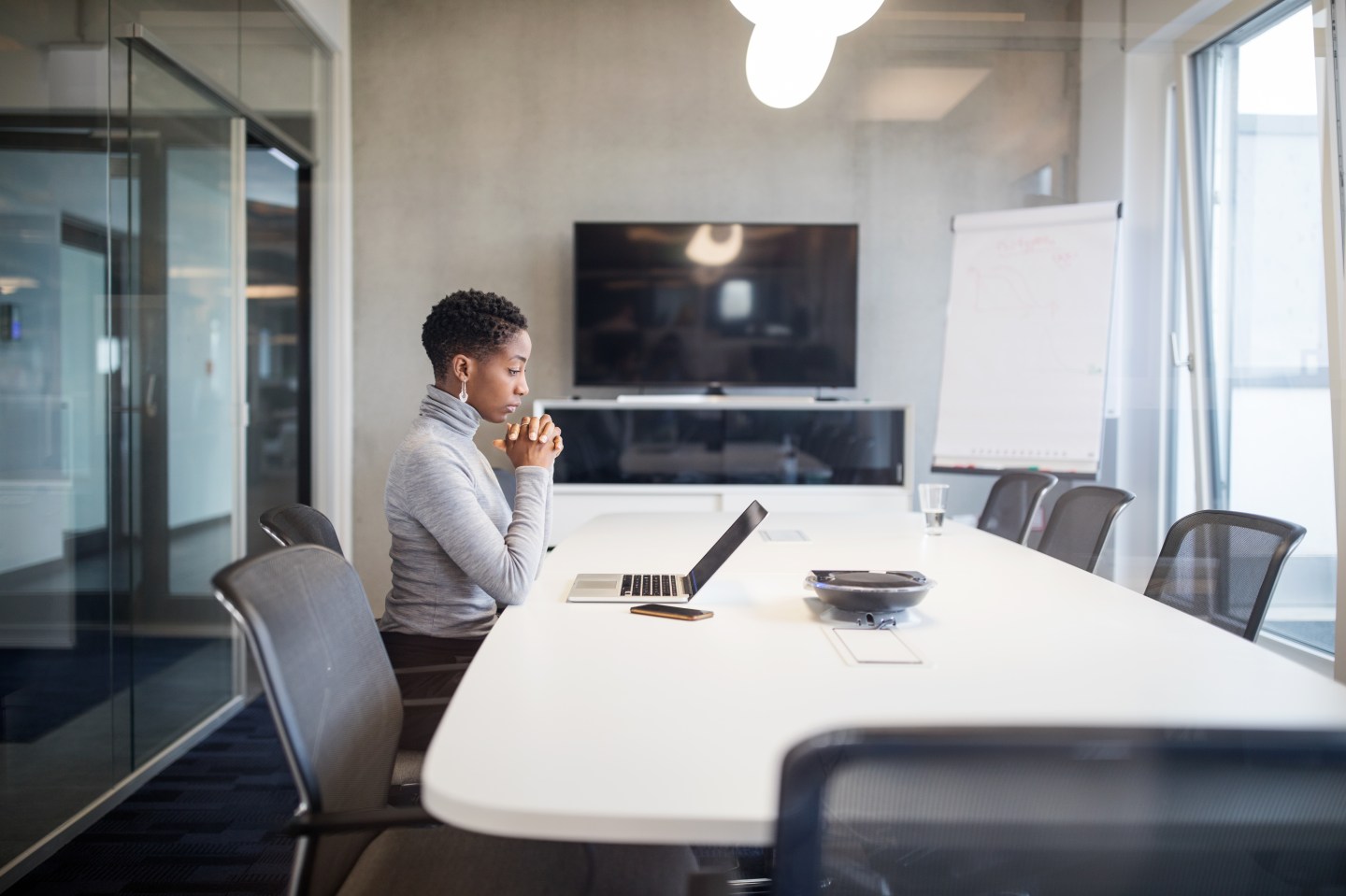 Side view of mature businesswoman looking at laptop and thinking. Mid adult female sitting at conference table with on laptop.