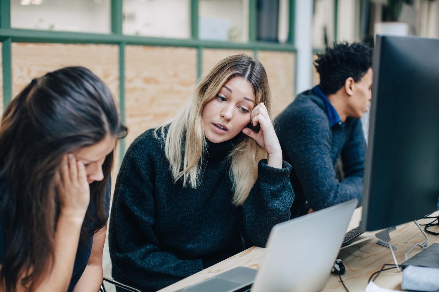 Two women look at a laptop screen.