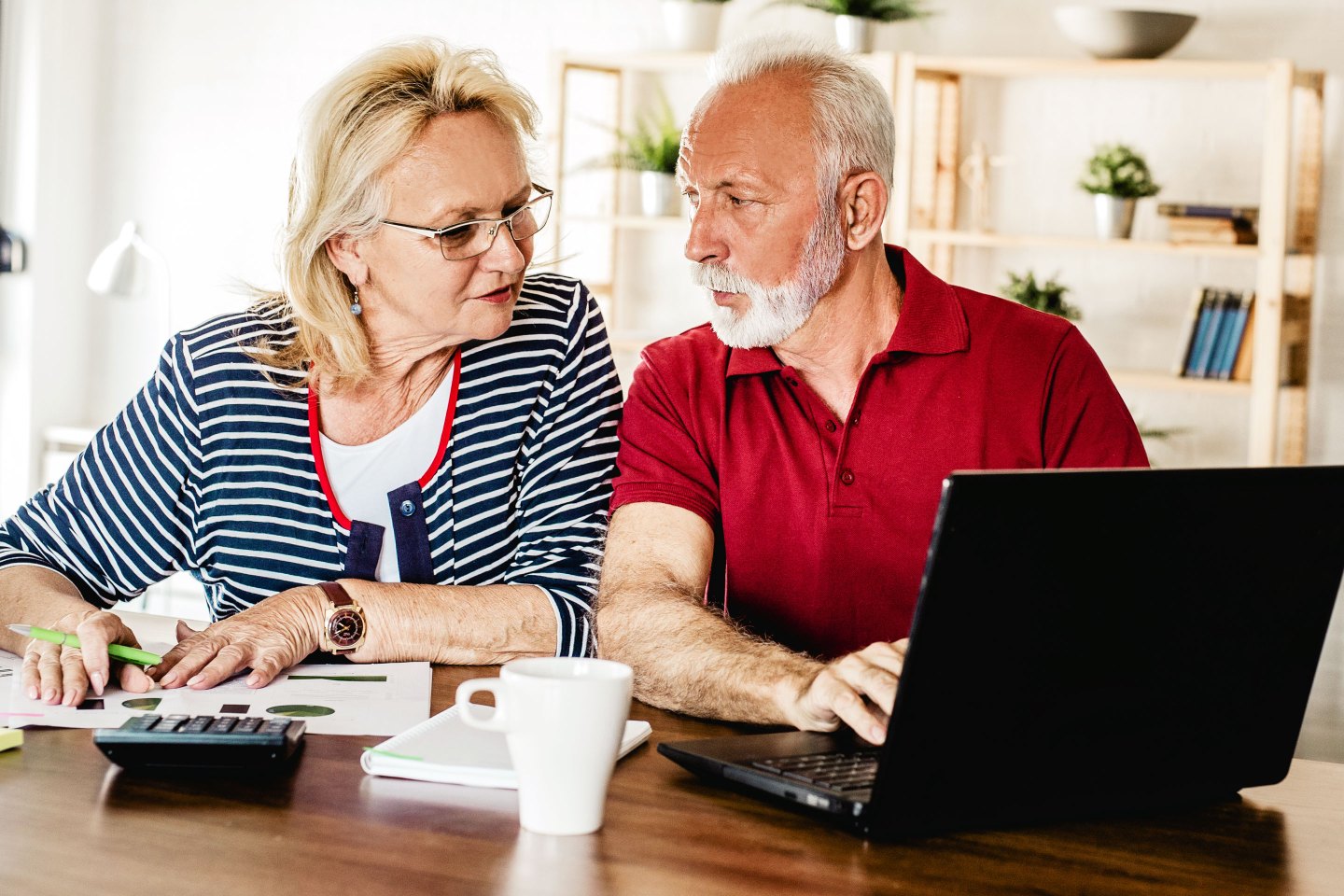 Senior couple sitting at the table, using laptop