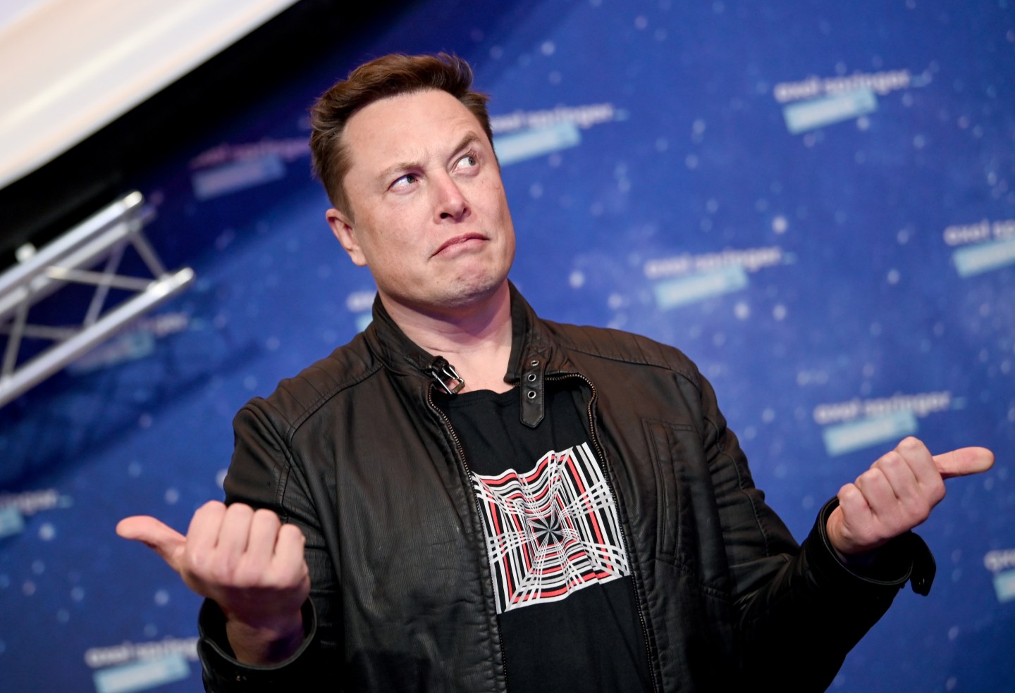 Twitter CEO Elon Musk with his thumbs to the side and a perplexed face