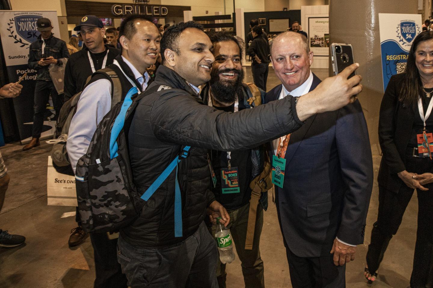 Greg Abel (right) poses for a selfie with three attendees at Berkshire Hathaway's annual meeting