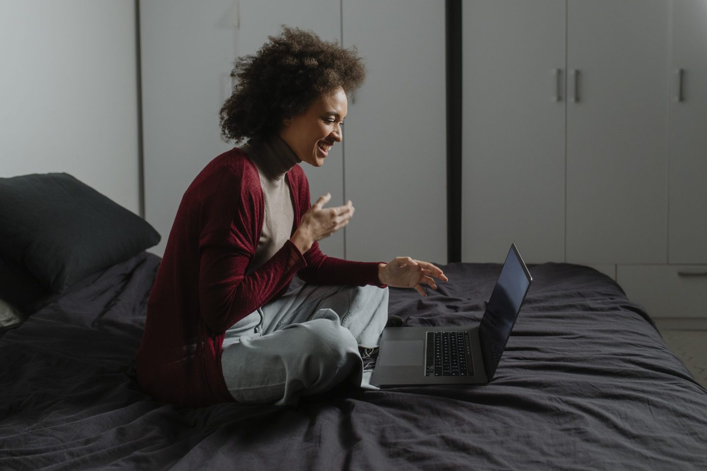 Woman happily working from home in bed