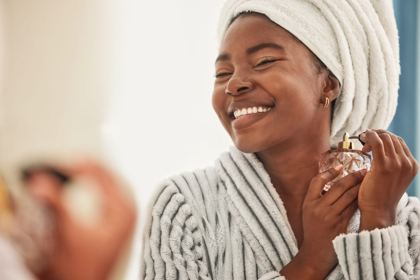 A young woman sprays herself with perfume from an unbranded bottle.