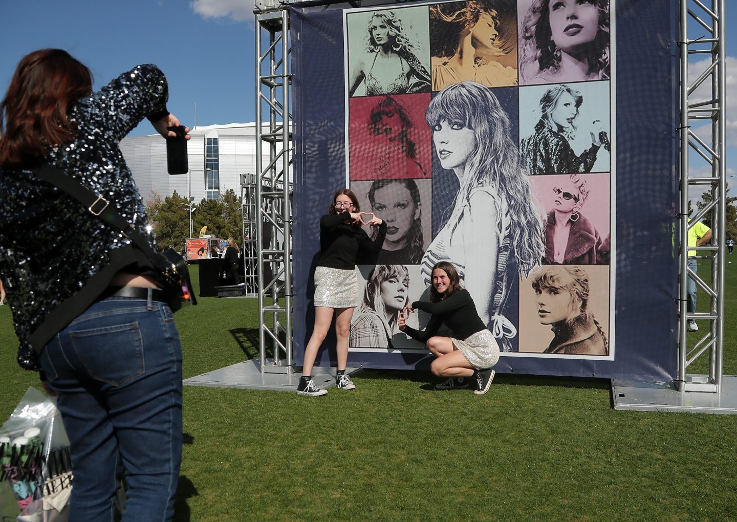 Young women standing in front of a Taylor Swift photo montage banner
