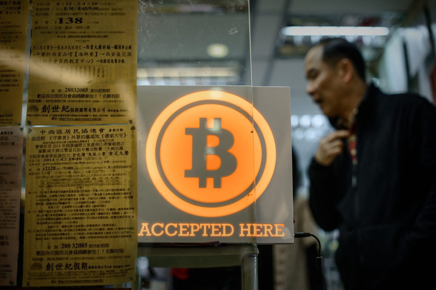 A man walks by a Bitcoin sign in Hong Kong