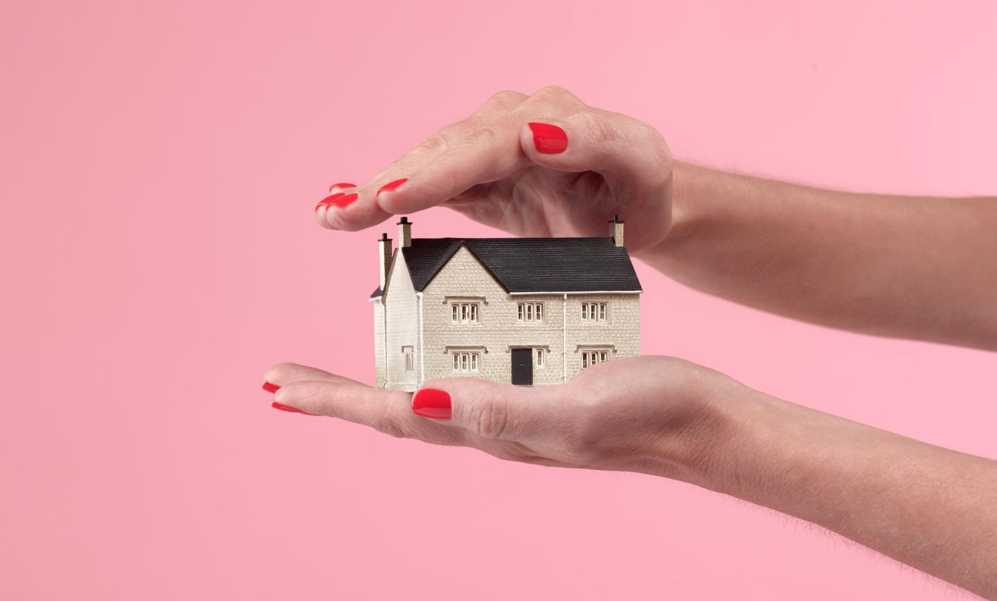 Two hands encompass a home model, showing how small it is.
