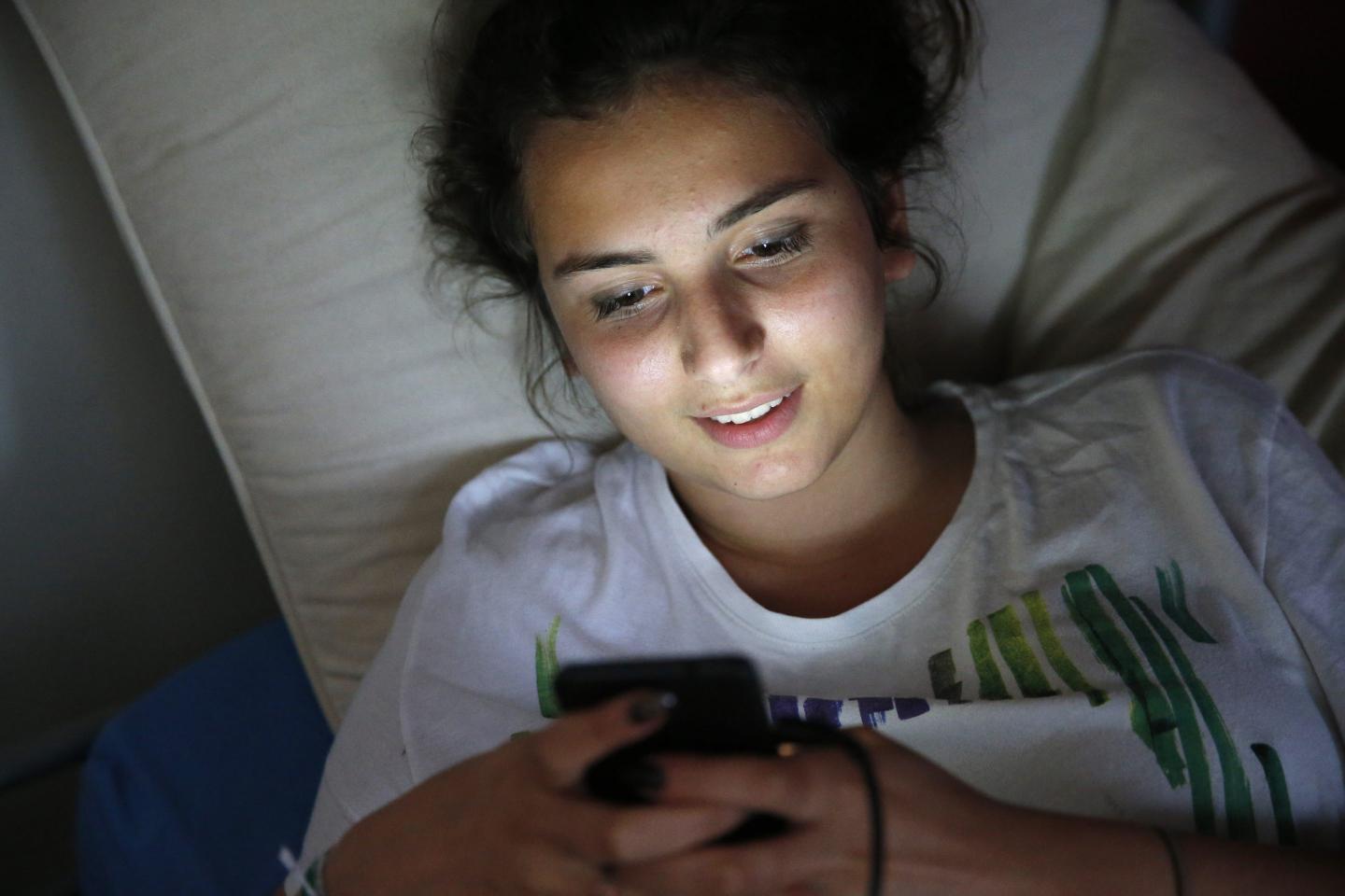 Teenager using a cell phone in bed