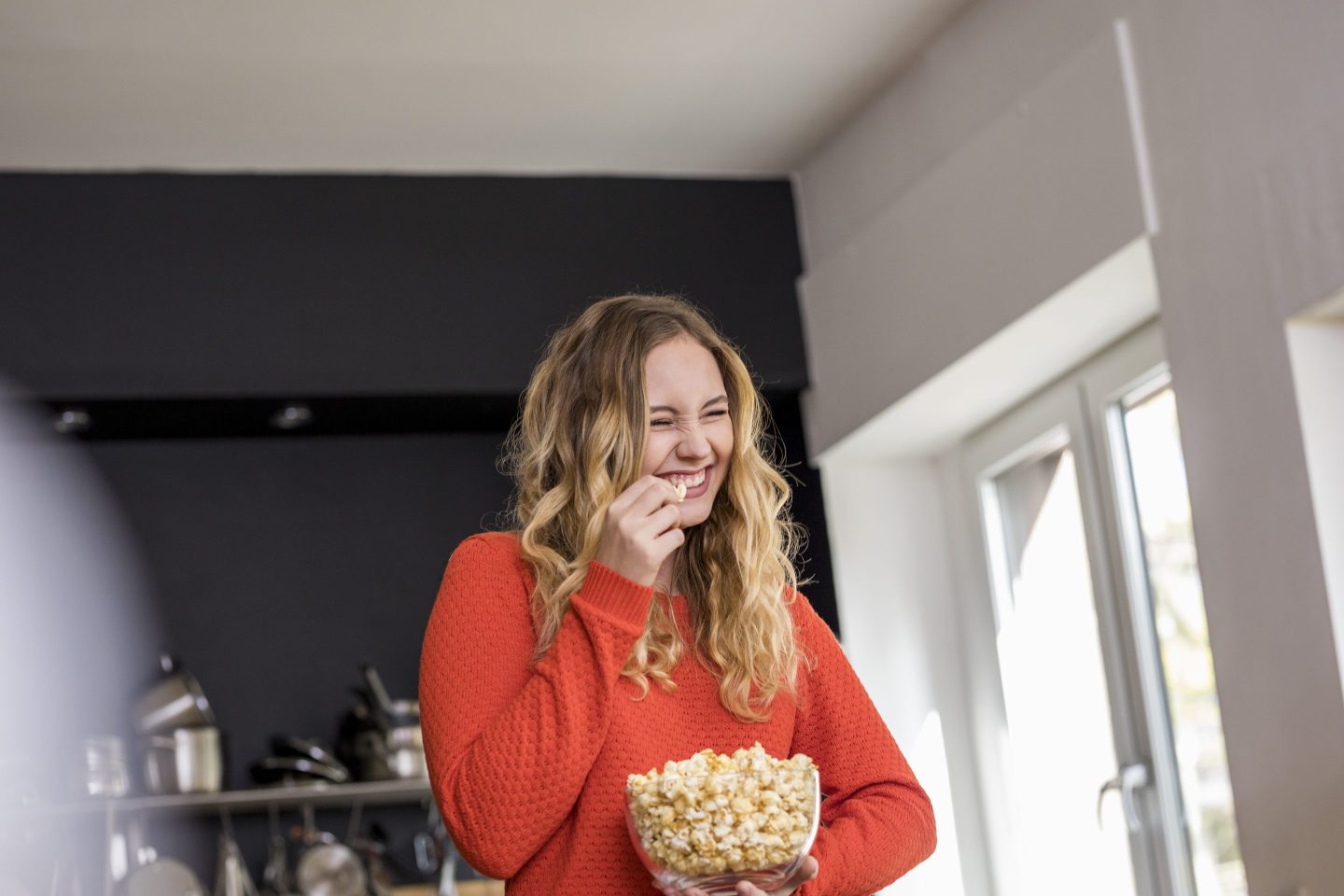A person smiling and eating a bowl of popcorn