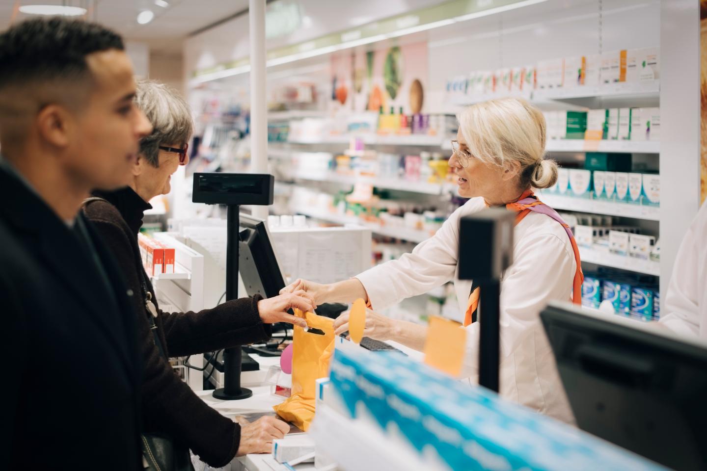 A pharmacist waiting on a customer at a pharmacy counter