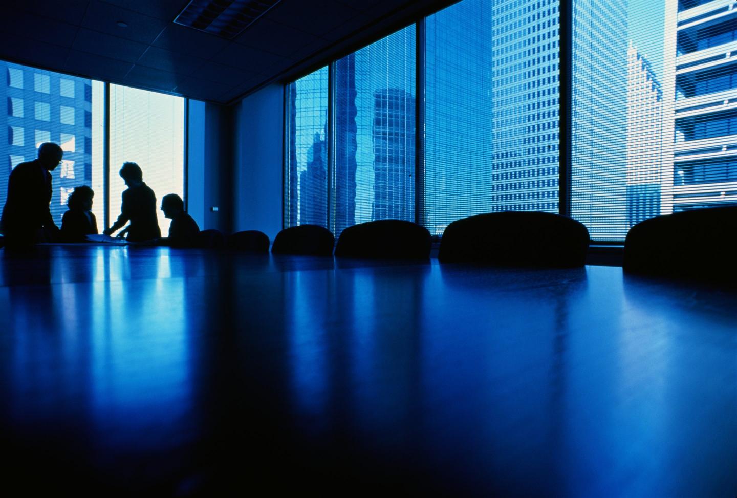 Directors huddle in a boardroom.