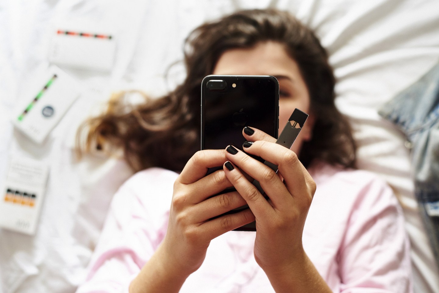 A person views a mobile device while holding a Juul Labs Inc. e-cigarette.